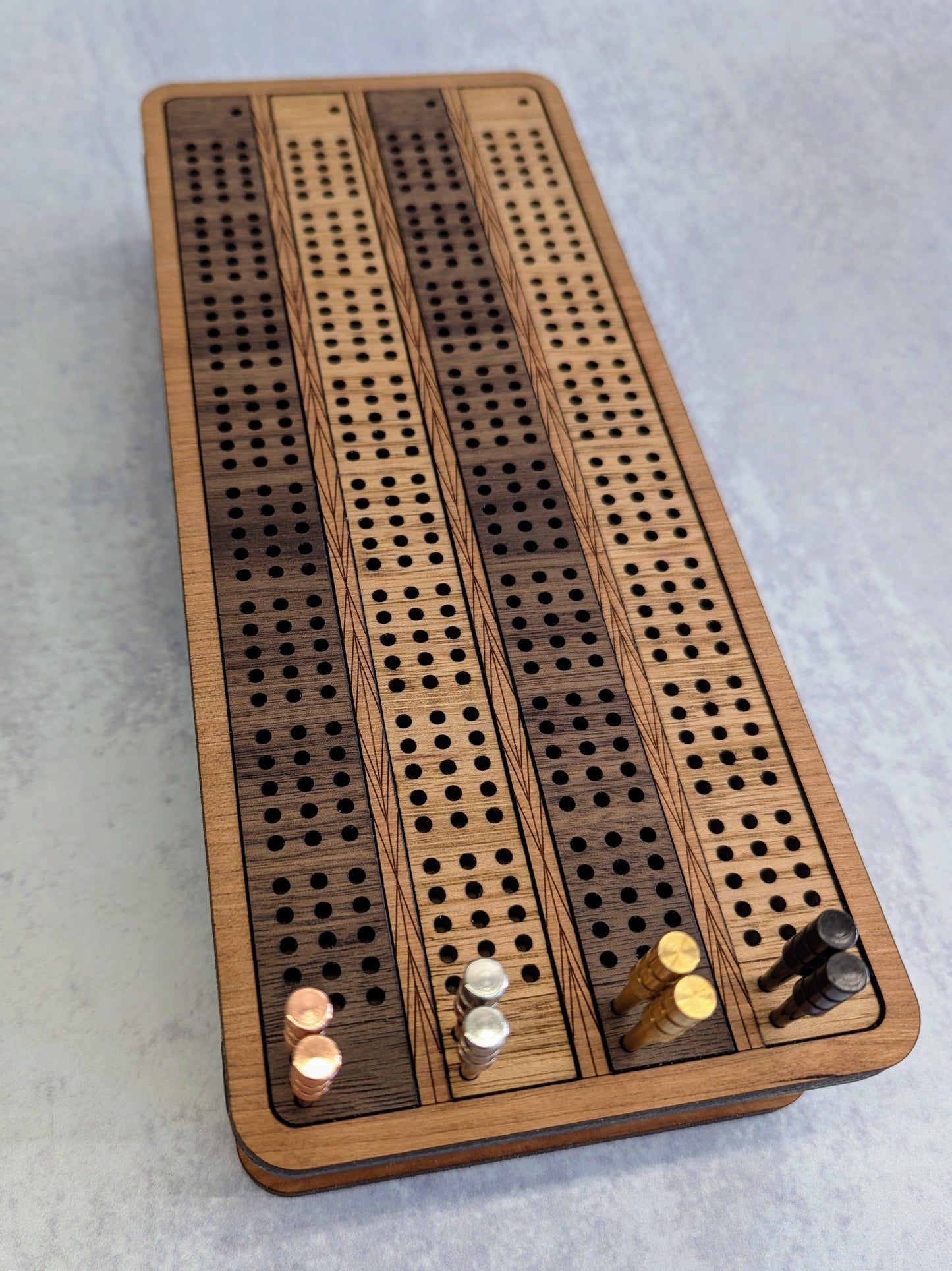 Close up view of top of 4 track cribbage board with pegs.
