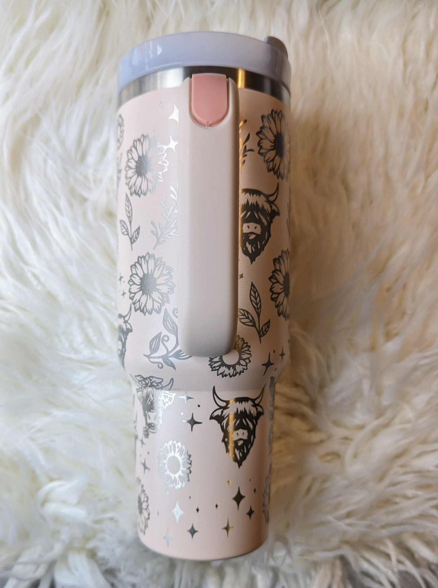 Photo of a soft pink colored 40 oz insulated tumbler with handle permanently engraved with a highland cow pattern and the text Live Like Someone Left the Gate Open