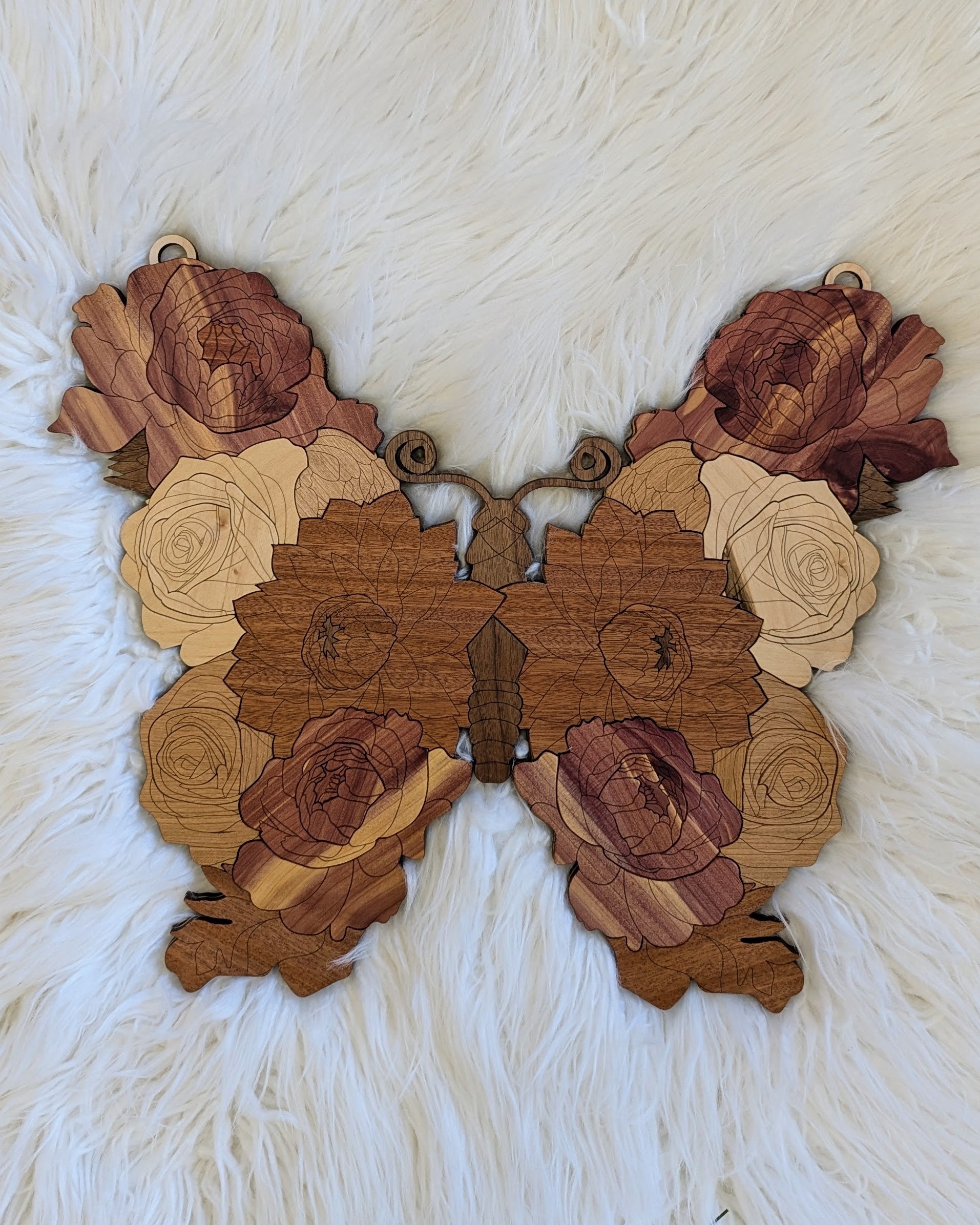 Flat lay of the finished butterfly on a white fur background, highlighting the soft lines and natural wood grain.