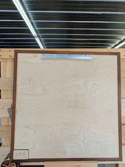 Wooden picture frame with a wooden panel inside, on a wooden pallet.