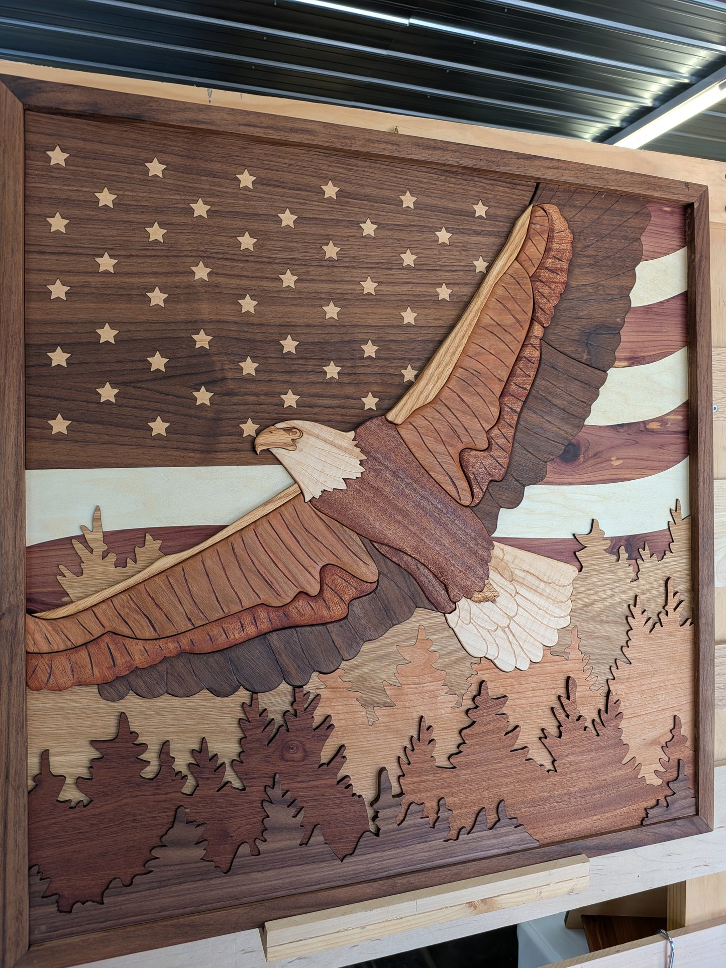 Wooden wall art with an eagle design on a background resembling an American flag.