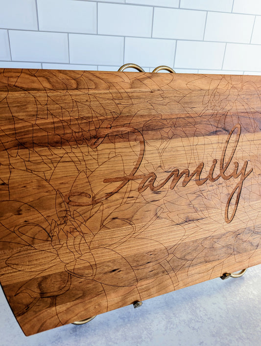 Solid cherry wood cutting board with floral markings and the word Family engraved in the center.