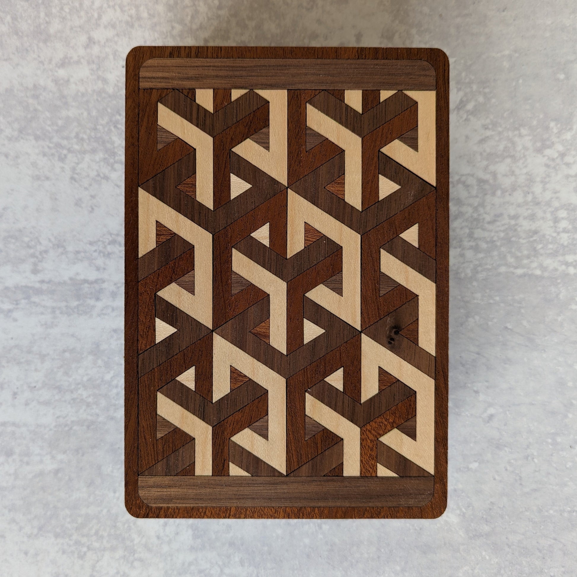 Handcrafted wooden playing card box made with layered cherry, walnut, maple, and mahogany veneer. Intricate geometric design on the lid with rich natural tones. Designed to hold two standard decks of cards.