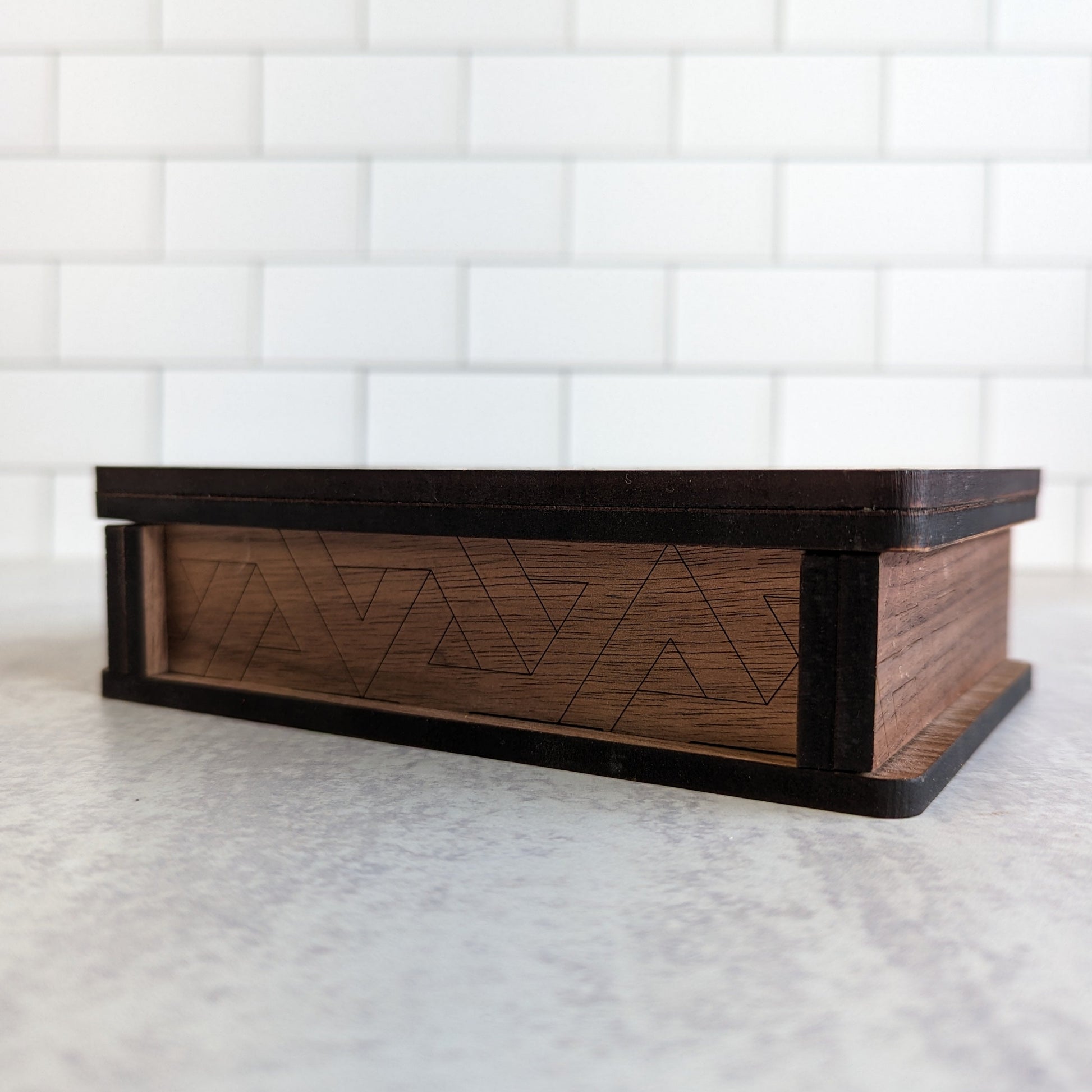 Handcrafted wooden playing card box made with layered cherry, walnut, maple, and mahogany veneer. Intricate geometric design on the lid with rich natural tones. Designed to hold two standard decks of cards.