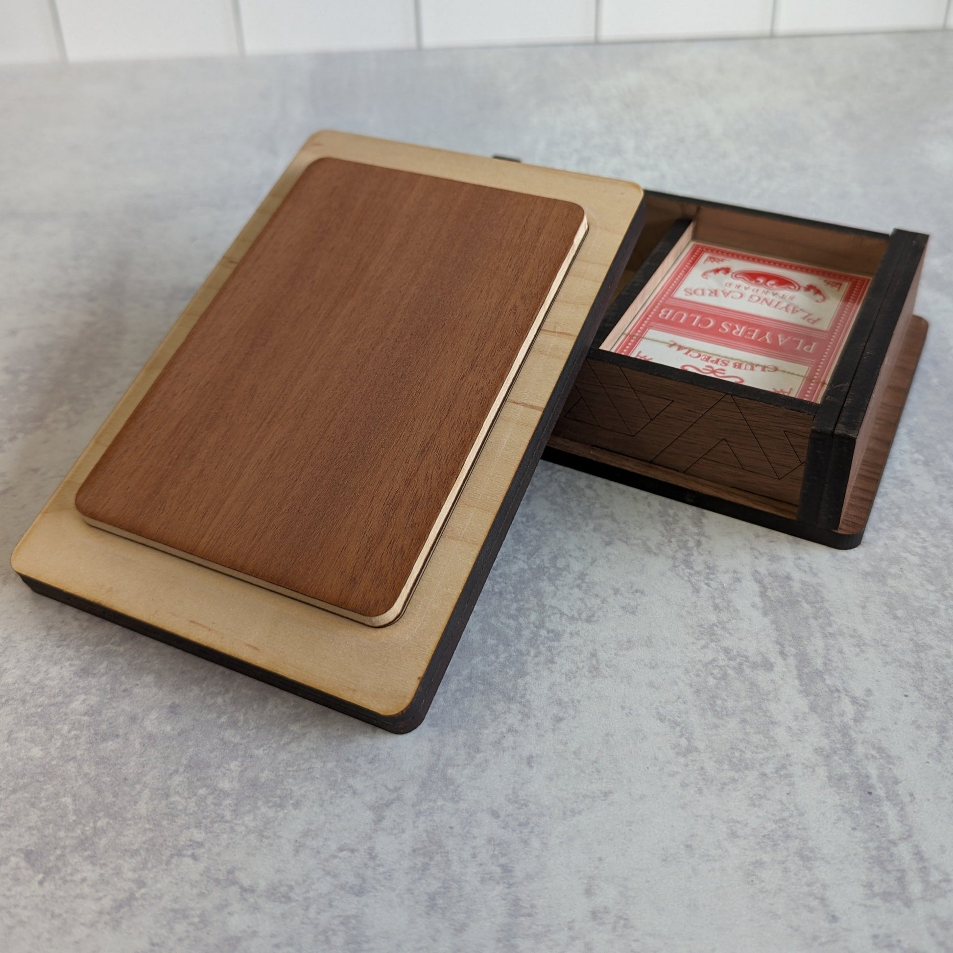 Interior view of handcrafted wooden playing card box with space for two decks of cards. Detailed woodwork on the inside and out.