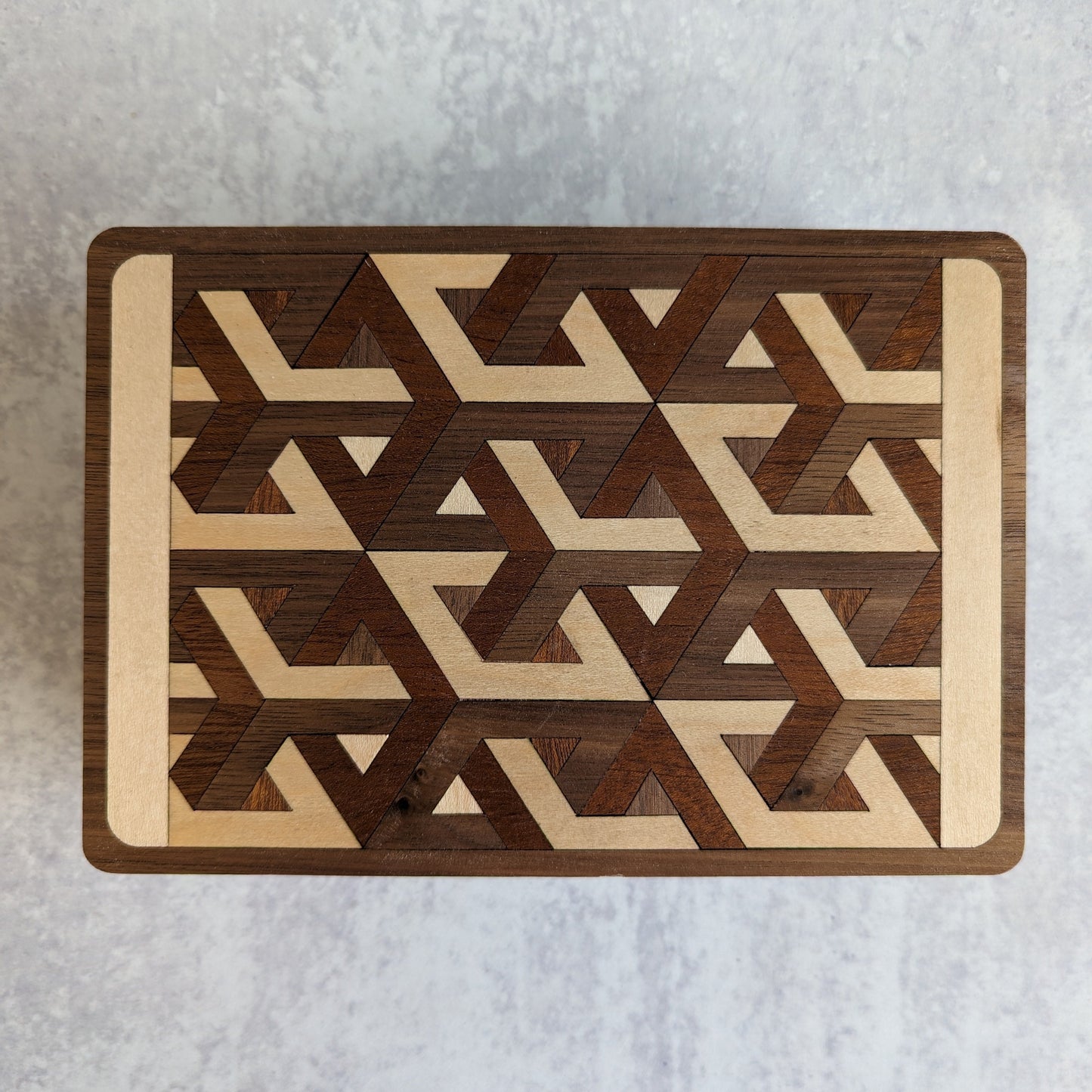Handcrafted wooden playing card box made with layered cherry, walnut, maple, and mahogany veneer. Intricate geometric design on the lid with rich natural tones. Designed to hold two standard decks of cards.