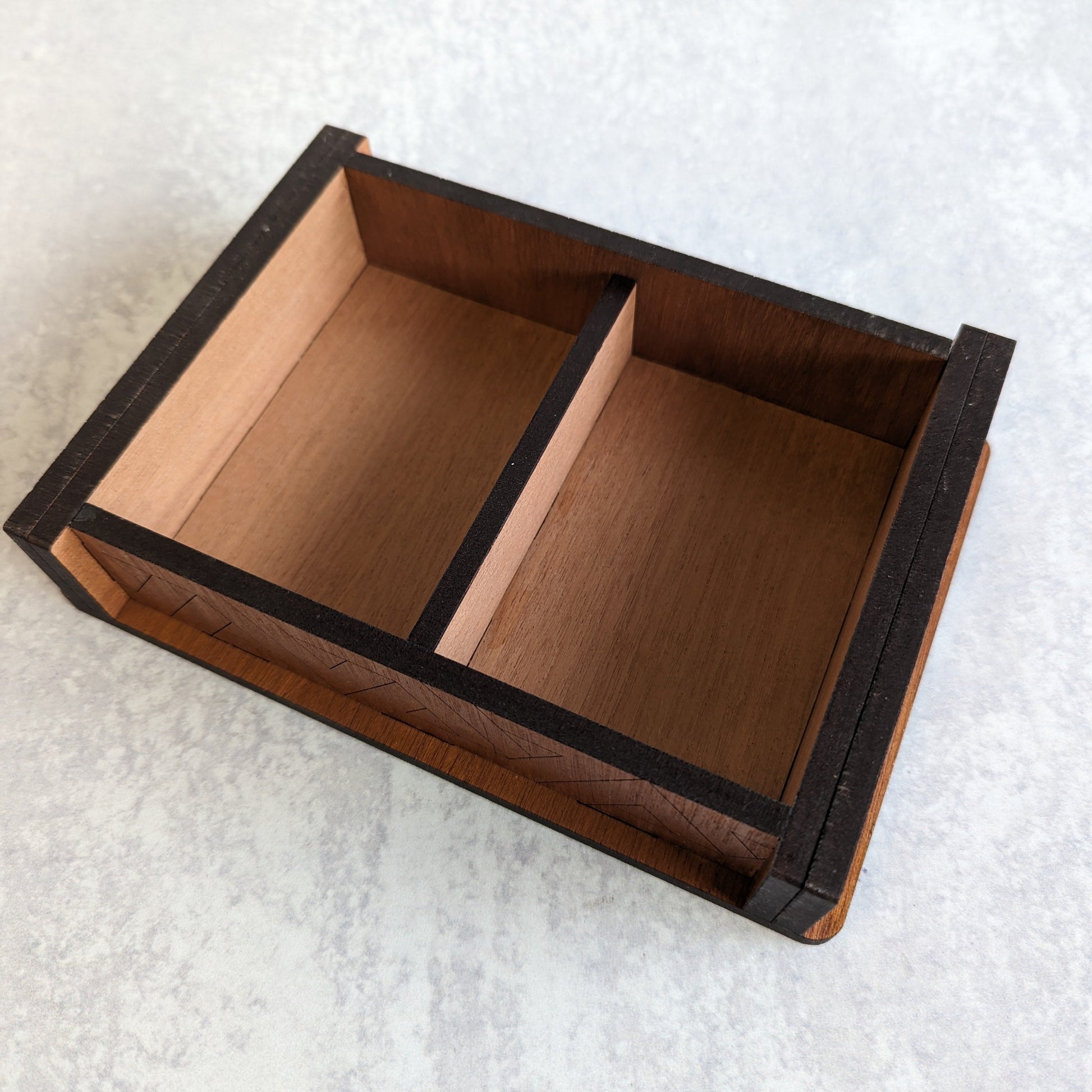 Interior view of handcrafted wooden playing card box with space for two decks of cards. Detailed woodwork on the inside and out.