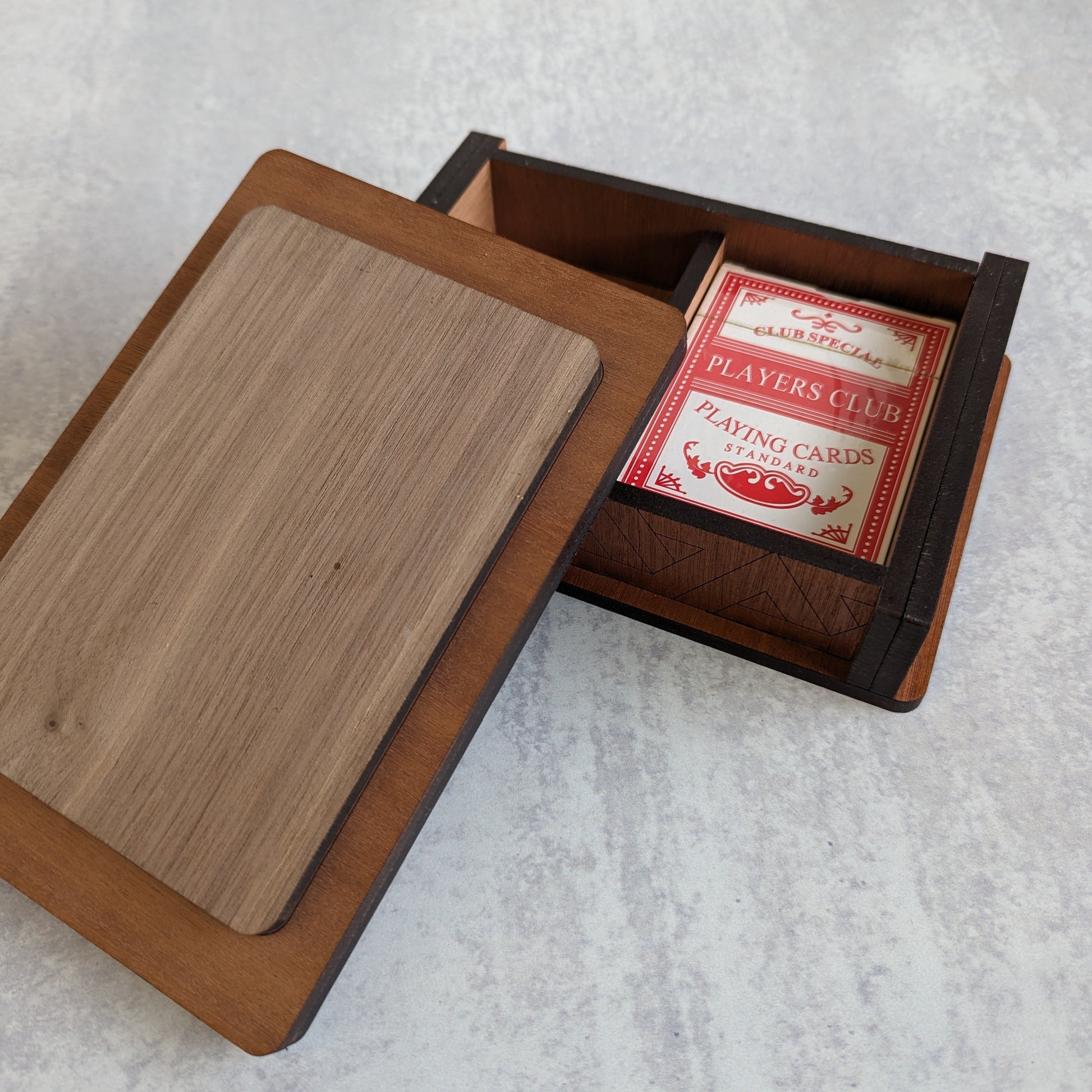 Handcrafted wooden playing card box made with layered cherry, walnut, maple, and mahogany veneer. Intricate geometric design on the lid with rich natural tones. Designed to hold two standard decks of cards.