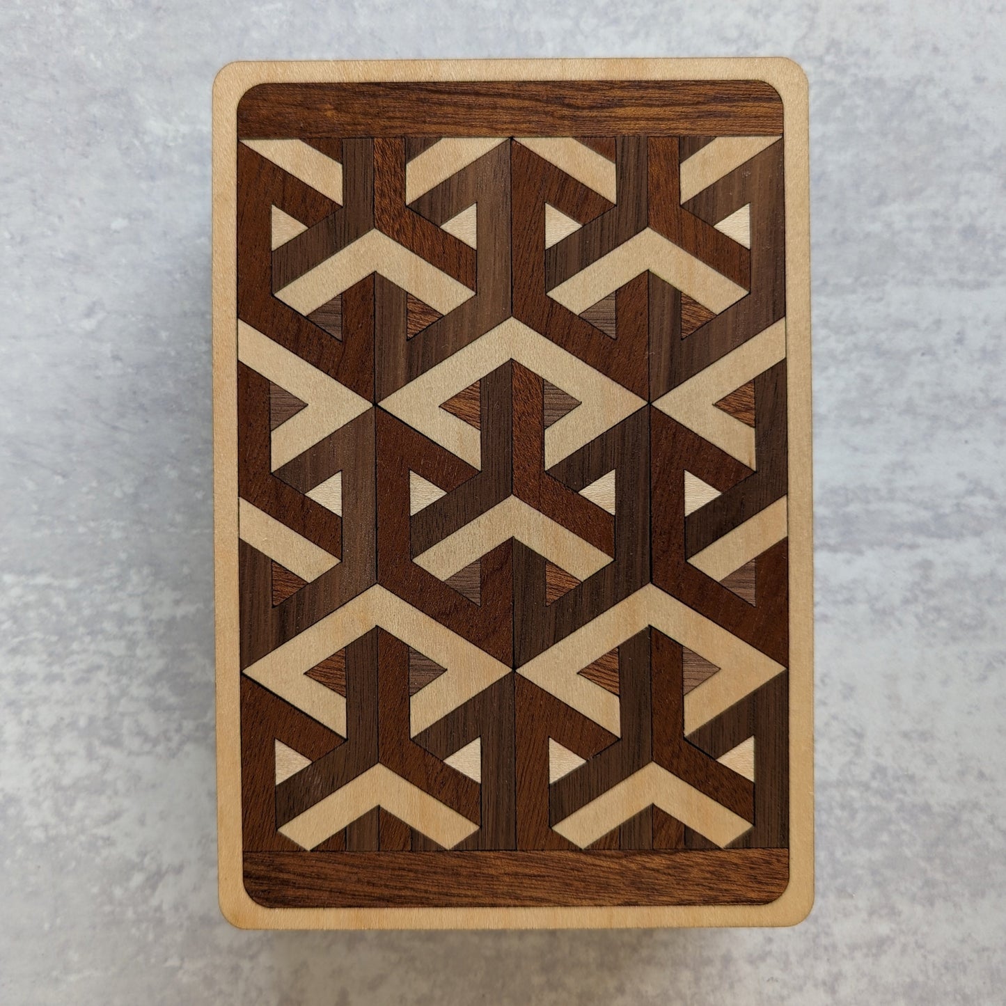 Handcrafted wooden playing card box made with layered cherry, walnut, maple, and mahogany veneer. Intricate geometric design on the lid with rich natural tones. Designed to hold two standard decks of cards.