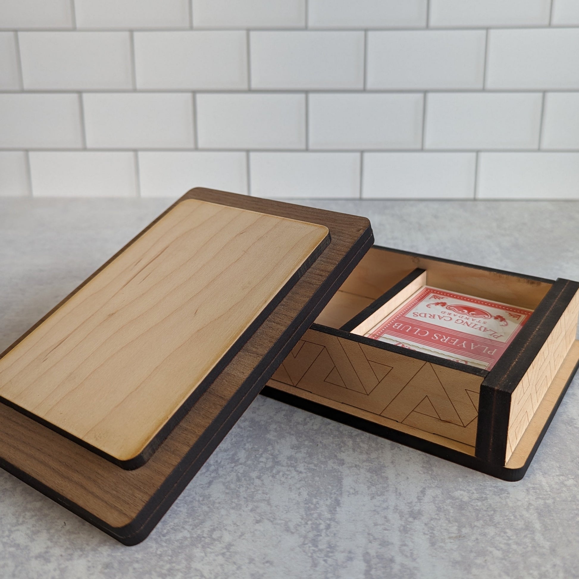 Handcrafted wooden playing card box made with layered  walnut, maple, and mahogany veneer. Intricate geometric design on the lid with rich natural tones. Designed to hold two standard decks of cards.