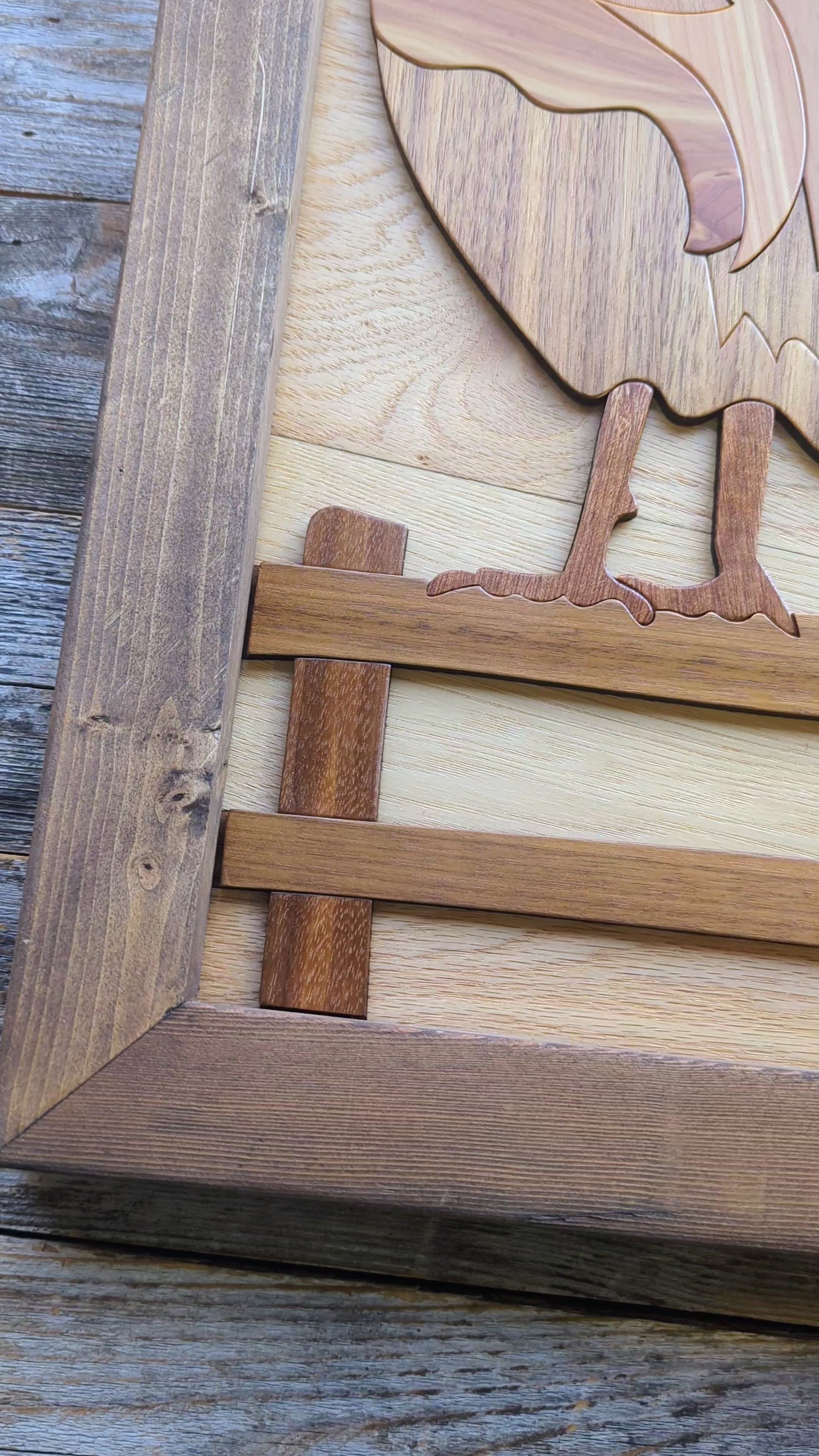 Video zooming in on the rooster’s foot on the wooden fence, highlighting detail and craftsmanship in the lower section.